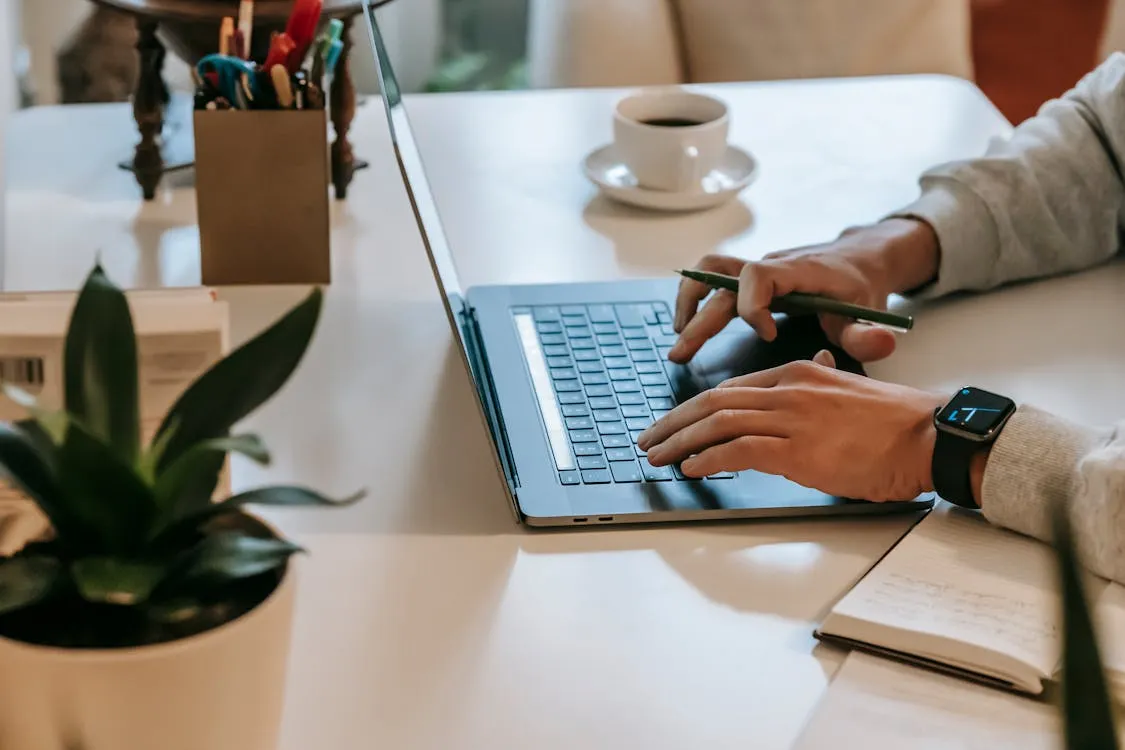 Freelancer working on a laptop to manage a Google Business Profile near a coffee cup and a notepad.