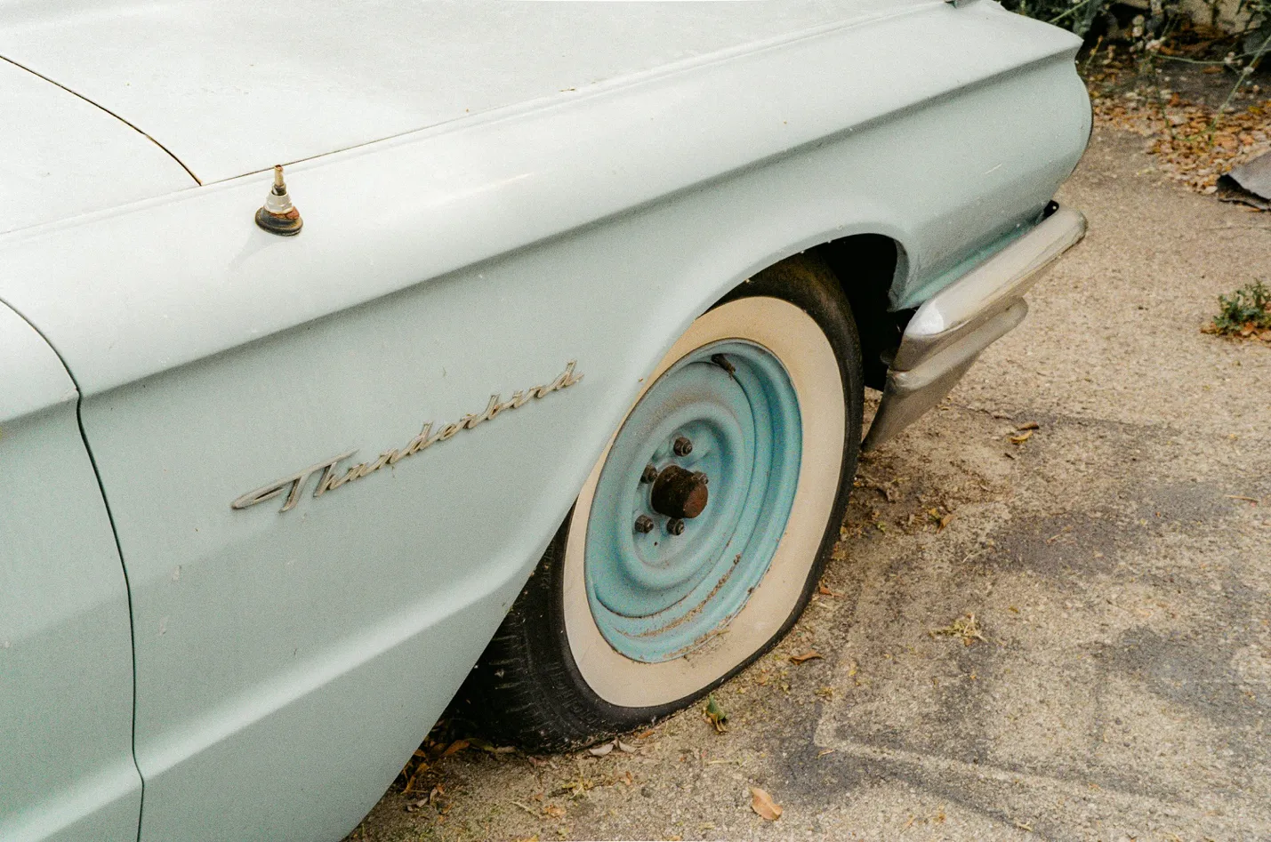 Ford Thunderbird with a flat tire parked on the side of the road