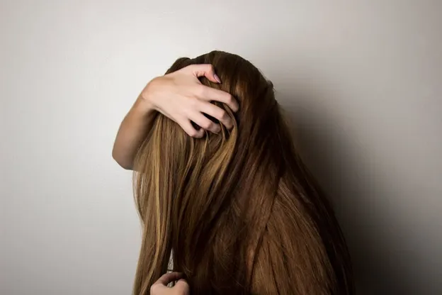 a woman scratching her head due to dandruff