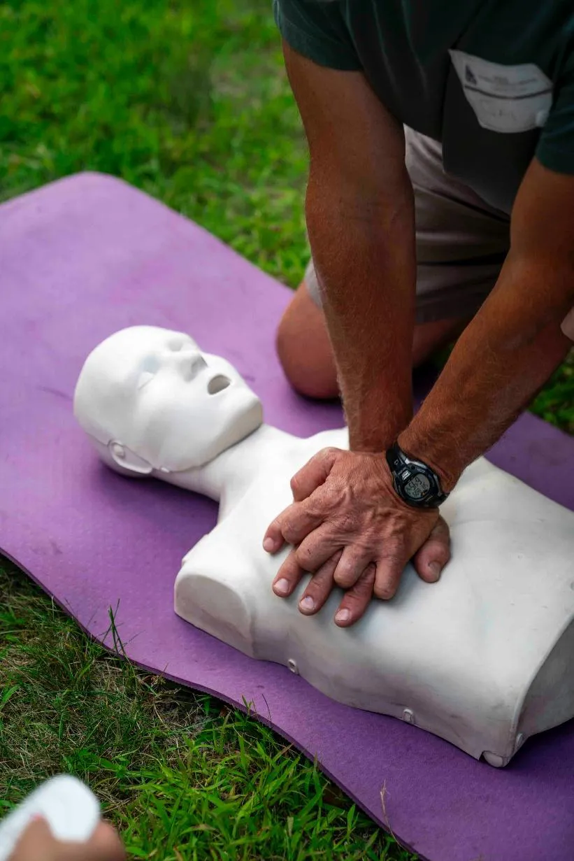 Person performing chest compressions on a CPR manikin during outdoor hands-on training