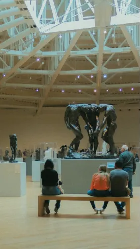 Museum gallery interior featuring statues and visitors observing exhibits