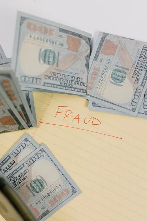 US dollars on a yellow sheet of paper with fraud written on it