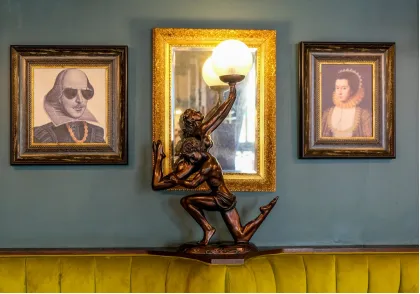 Gold-framed portrait paintings and a bronze sculpture displayed in a luxury interior.