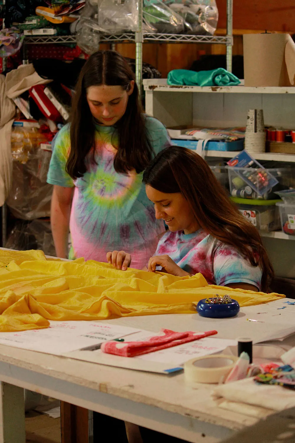 Two campers work together on a creative arts project using clothespins and craft materials during an art class.