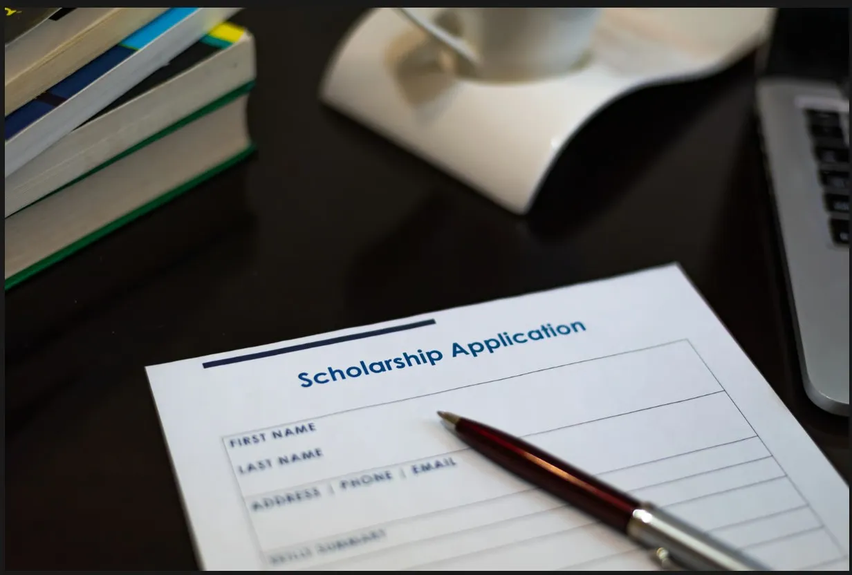 Printed college scholarship application paper with a pen on a study desk, representing financial aid and student admissions.