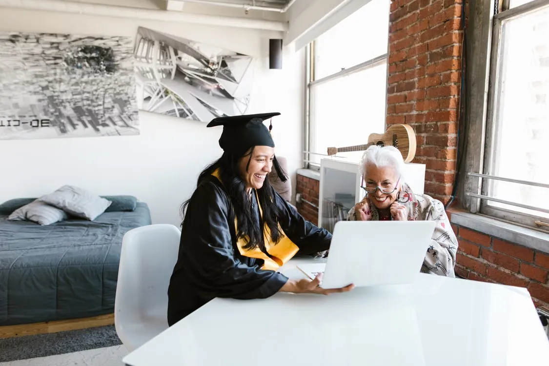 An elderly person and their child using a laptop together 