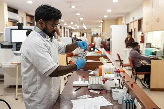Indian laboratory technician working in a hospital laboratory while handling clinical samples and diagnostic equipment.