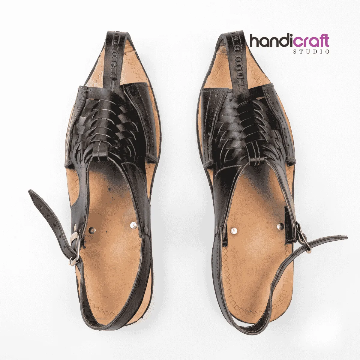 Top-down view of a pair of black handcrafted leather Chamba Chappal sandals featuring a traditional pointed-toe design, intricate braided leather vamp straps, adjustable ankle buckles, and a light tan leather sole with white background framing.