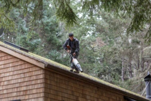a men on roof cleaning the roof with blower