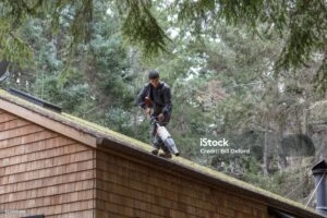 a men on roof cleaning the roof with blower