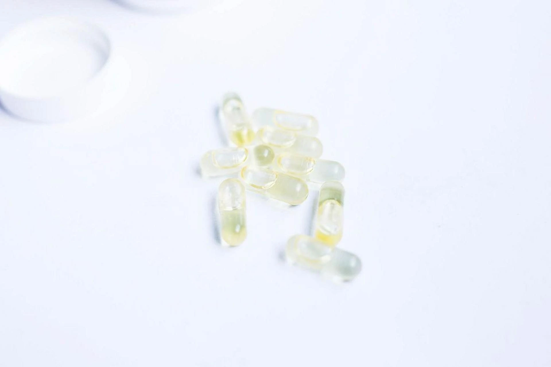 White capsules with powder and one open on a black background ...