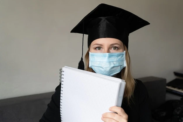 Girl in medical mask with graduation gown hat holding a notebook on grey background