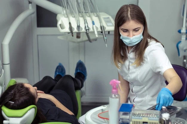 Dentist at work preparing instruments for examining woman\'s teeth in dental clinic