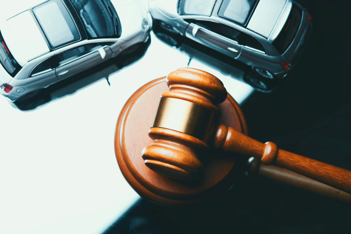 A wooden gavel placed with two small toy cars