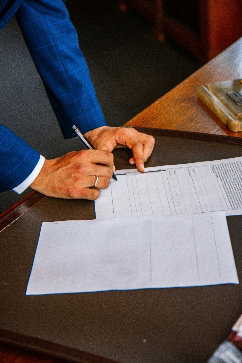 Executive signing a document at a desk during a business transaction