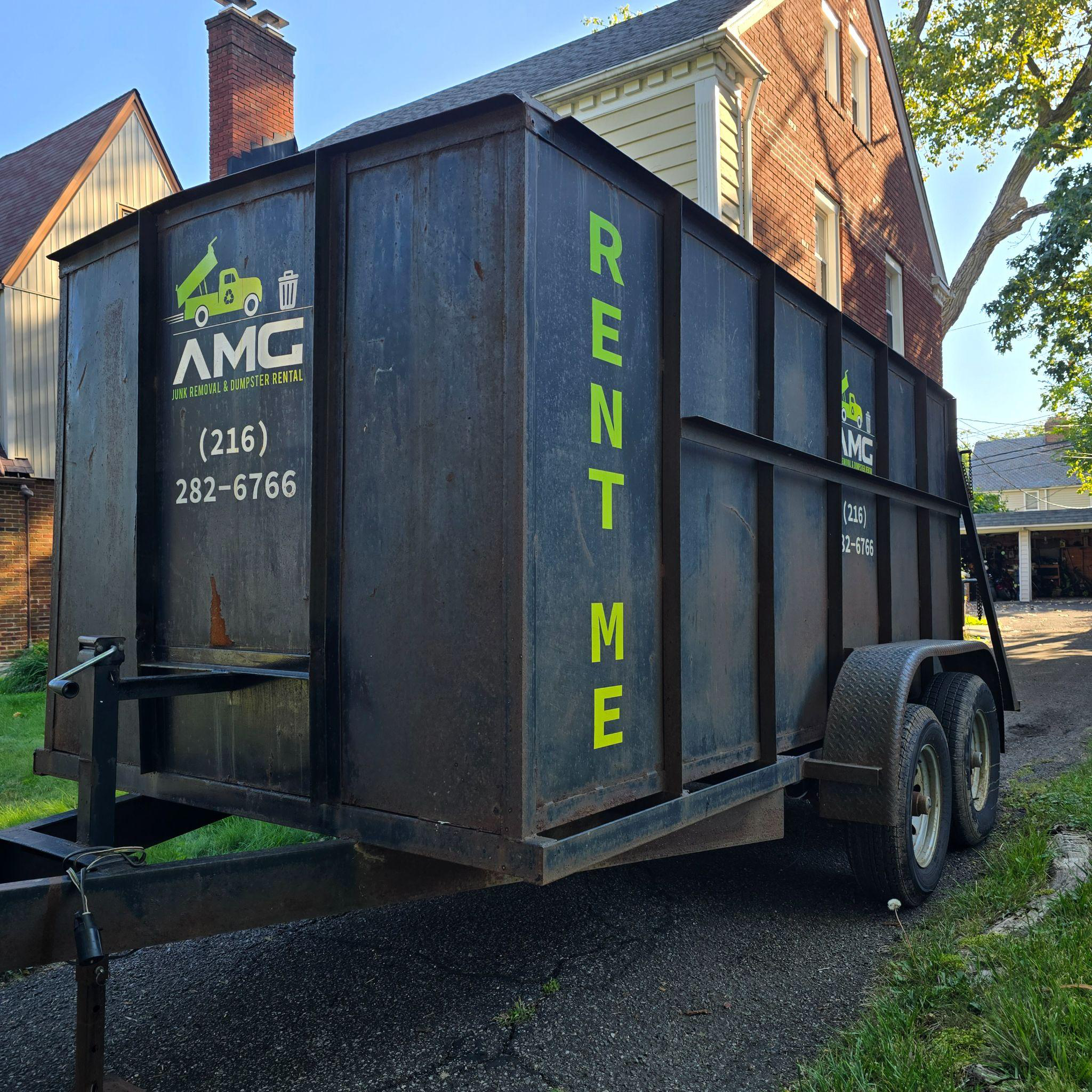 Dumpster positioned in a driveway to manage debris from a full-property cleanout by AMG.