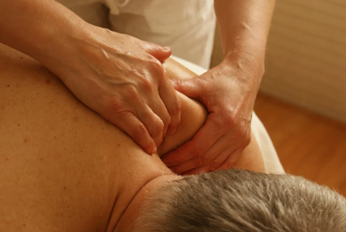 Therapist applying deep pressure to the upper back during a massage