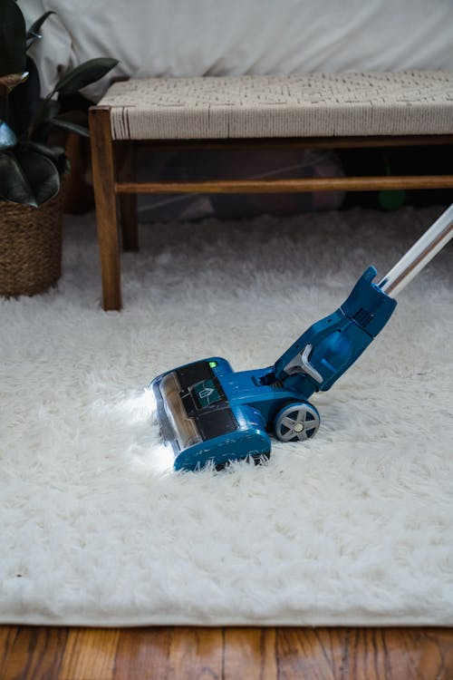 close-up of a blue vacuum on a white fur carpet