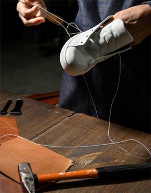 Jasperosso shoemaker hand stitching a pair of men’s leather sneakers.