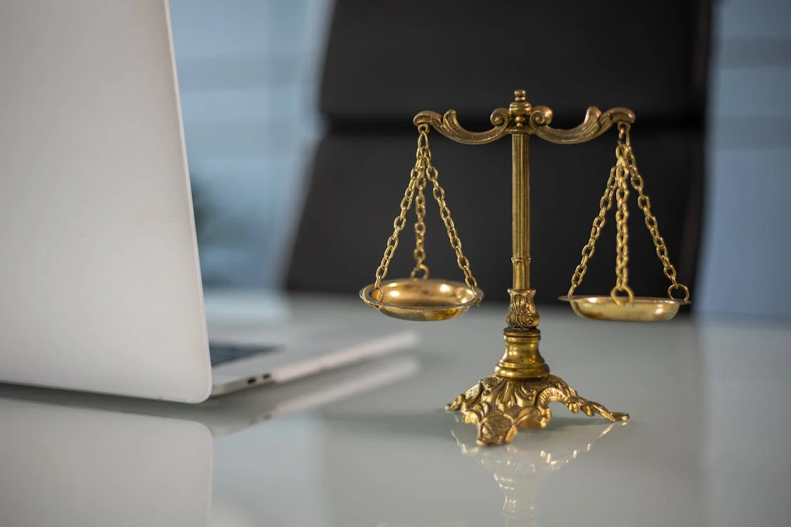 a golden balance scale beside a laptop on a lawyer's table