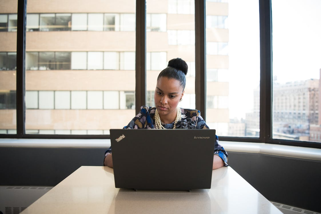 Woman working at desk near large window with bright daylight