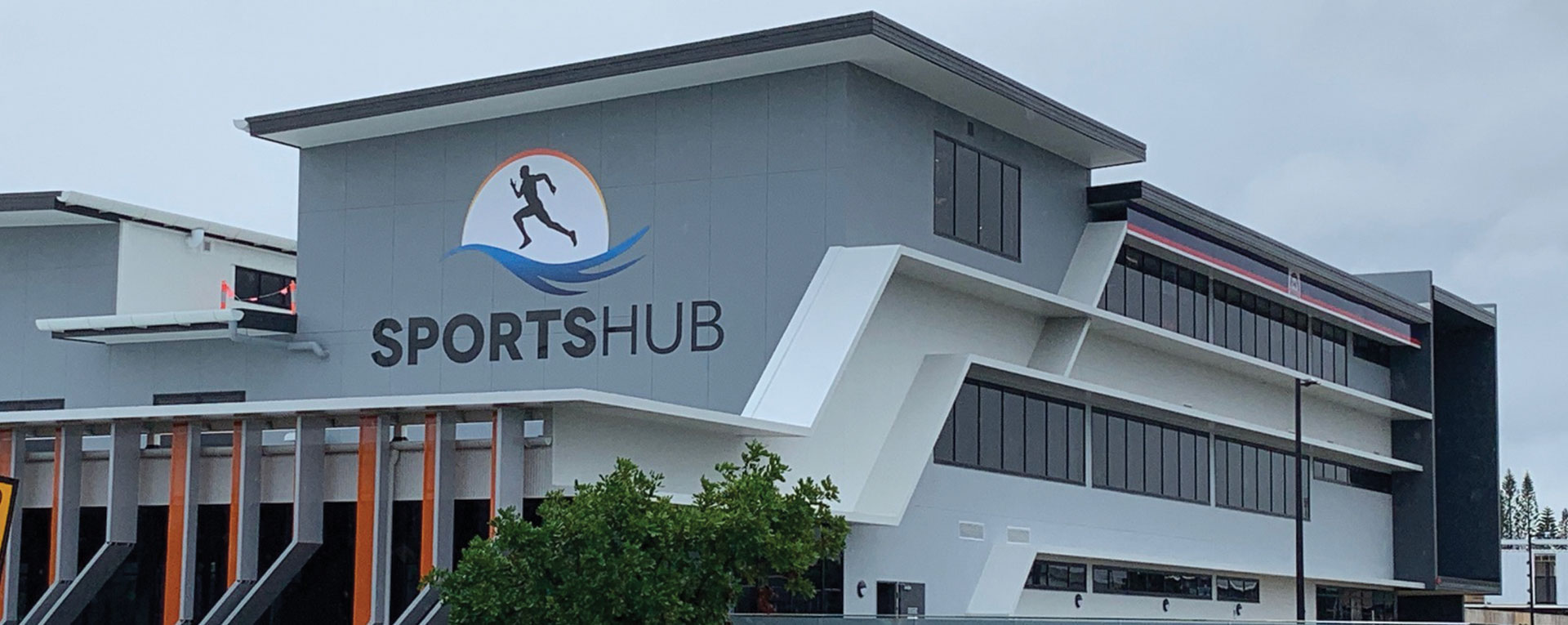 Large SportsHub building signage installed on the exterior of a modern commercial sports facility with a running logo on the facade.