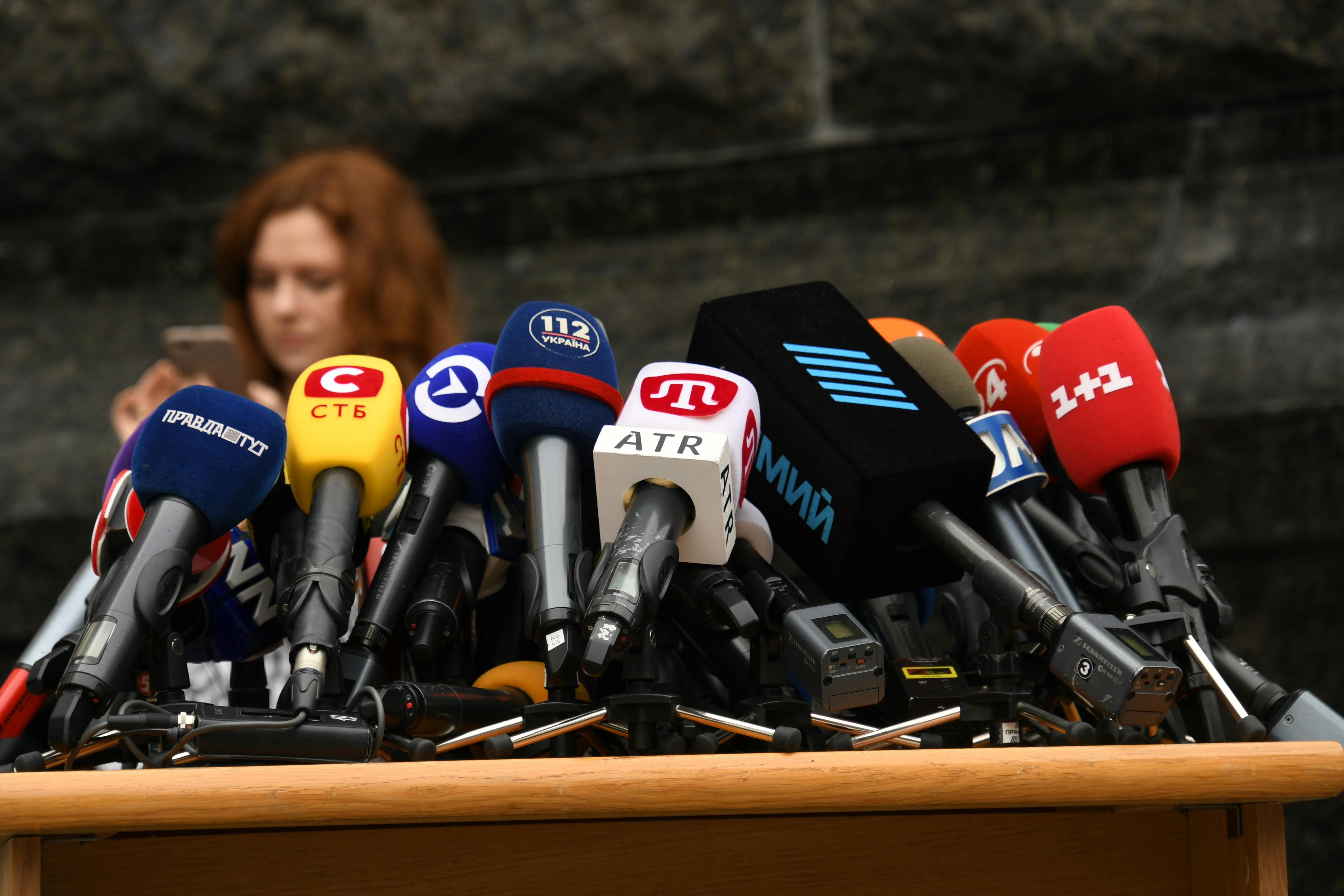 Cluster of microphones arranged on a table before a press conference.