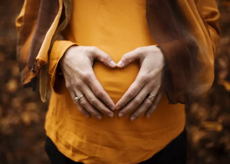 A woman’s hands over her baby bump