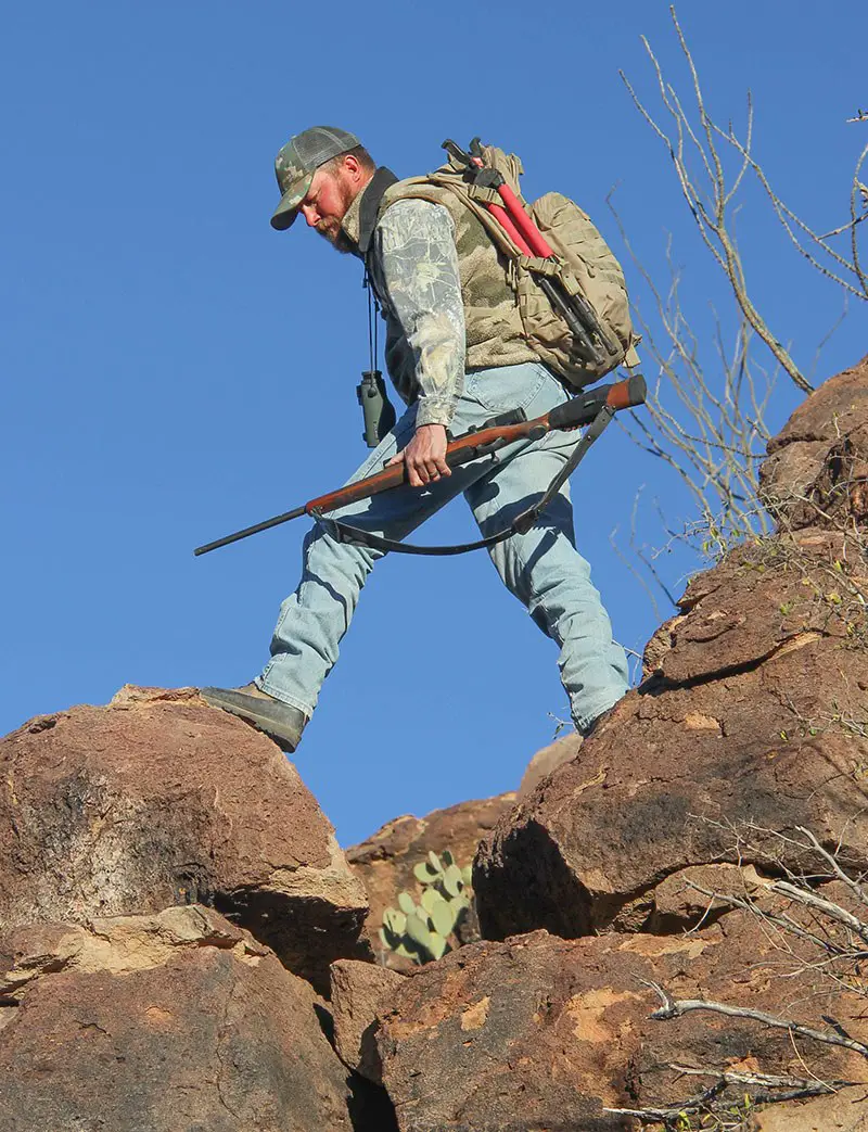 Man Climbing Rock with hunting shotgun-892d2a8c
