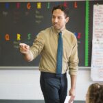 teacher-pointing-while-teaching-in-classroom-962347986-75ce5f976522477686ca12d3e7972054-b08a3e3f