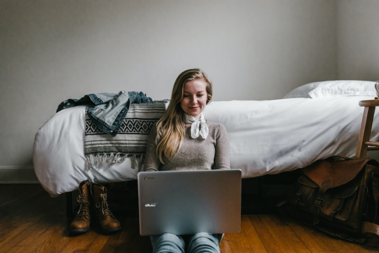 Smiling woman using laptop in her bedroom