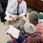 senior-couple-meeting-with-male-financial-advisor-at-home-and-signing-document-1-e602bd30