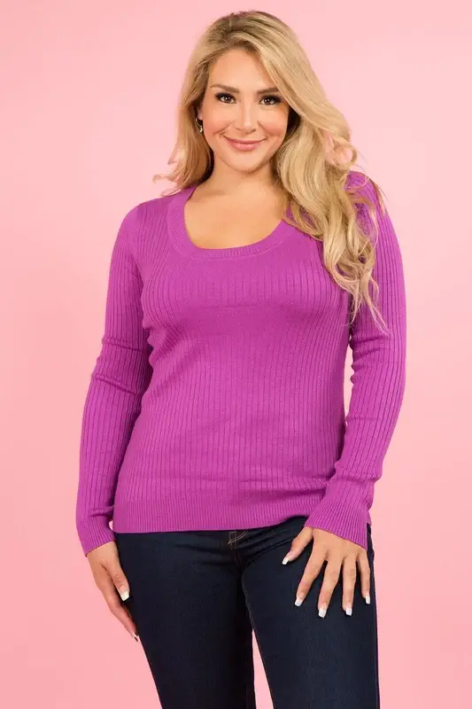 A curvy woman wearing a magenta sweater with dark jeans