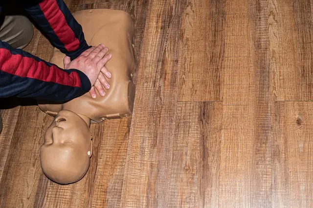 A medical professional practicing CPR on a dummy doll during a CPR class