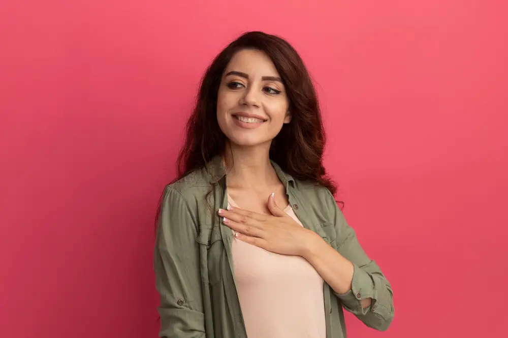 smiling-looking-side-young-beautiful-girl-wearing-olive-green-t-shirt-putting-hand-chest-isolated-pink-wall