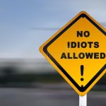 funny-road-sign-no-idiots-allowed-exclamation-mark-text-set-against-speed-blurred-background-140649531