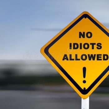 funny-road-sign-no-idiots-allowed-exclamation-mark-text-set-against-speed-blurred-background-140649531