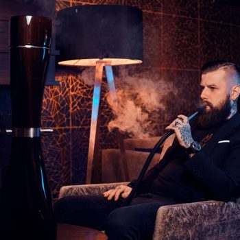 pensive-tattooed-man-is-sitting-armchair-starting-smoke-hookah-there-are-nice-vapour_613910-20763