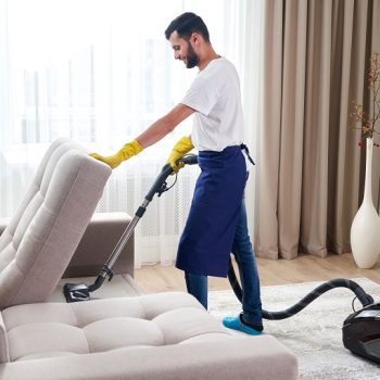 young-man-cleaning-sofa-with-vacuum-cleaner-leaving-room-home2