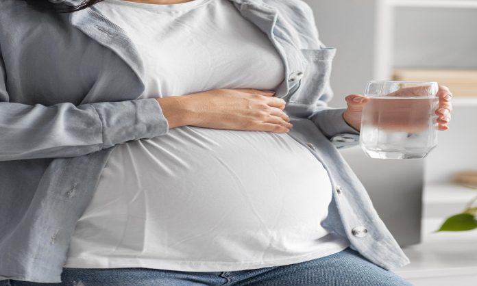 pregnant-woman-home-holding-glass-water-696x418