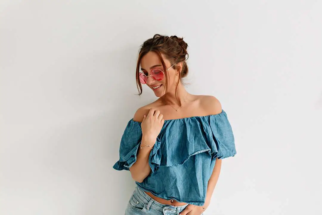 stylish-attractive-pretty-girl-with-tanned-skin-dark-hair-wearing-denim-top-pink-glasses-is-posing-against-isolated-wall