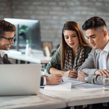 Man-In-Gray-Suit-Pointing-To-A-Document-For-A-Male-and-Female-Client