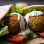 204886513-macro-shot-of-falafel-wrap-with-lettuce-tomatoes-cucumbers-and-falafel-balls-drizzled-with-tahini