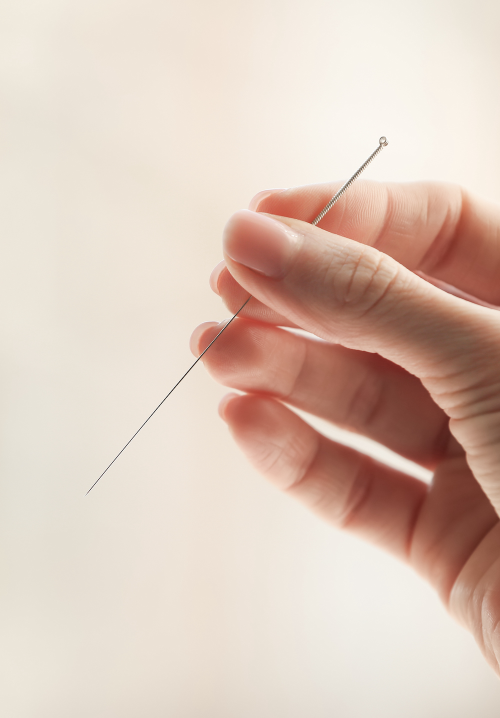 female-hand-with-needle-acupuncture-blurred-background