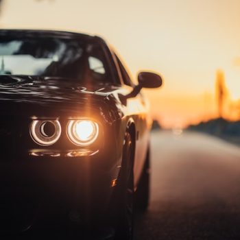 luxurious-car-parked-highway-with-illuminated-headlight-sunset_181624-60607