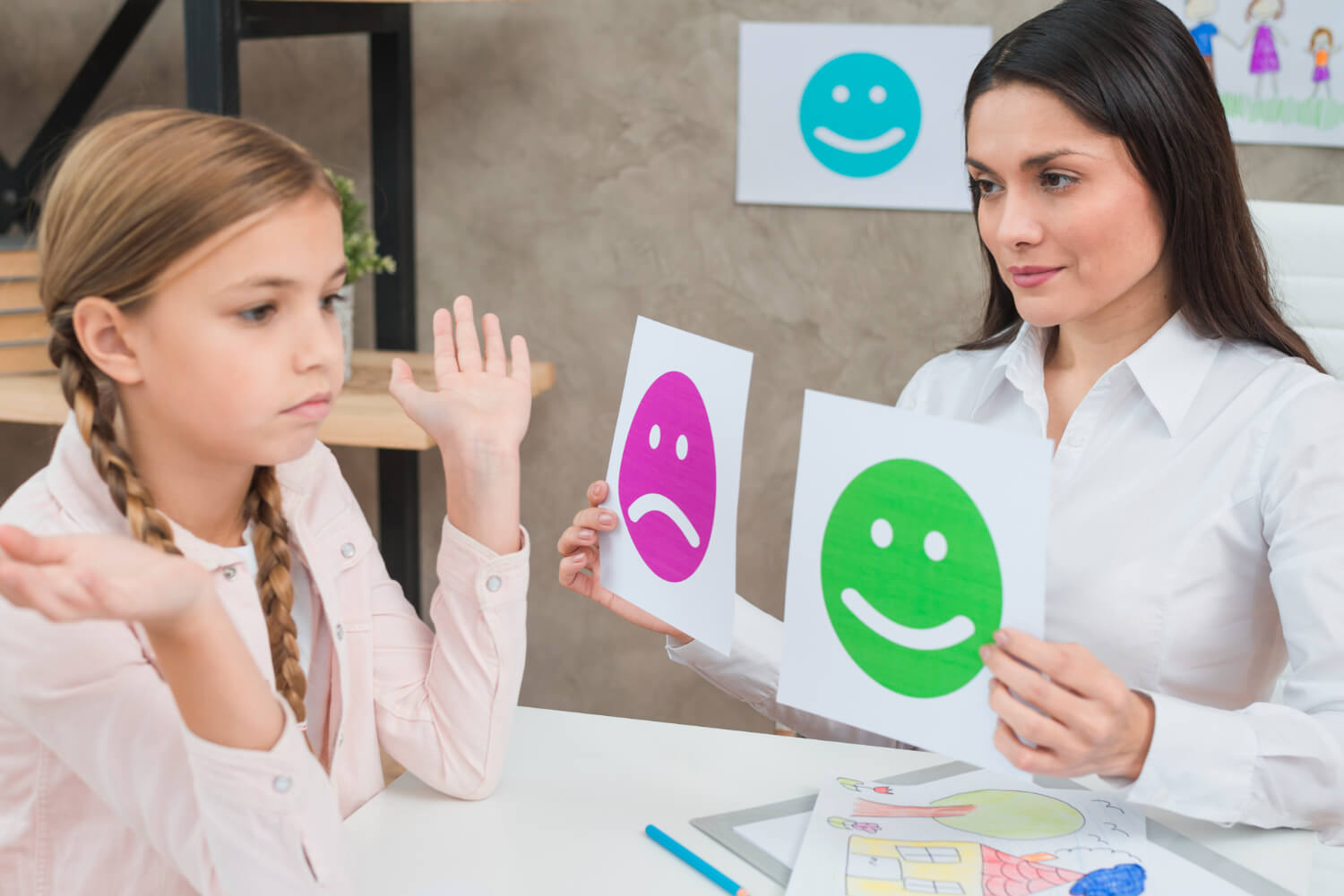 smiling-psychologist-showing-happy-sad-emotion-faces-cards-girl-child (1)