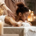 tender-african-woman-smiling-enjoying-massage-with-closed-eyes-spa-resort