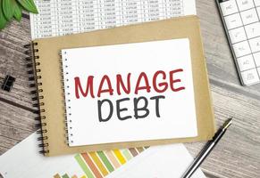 text-manage-debt-on-notepad-and-pen-on-wooden-background-photo