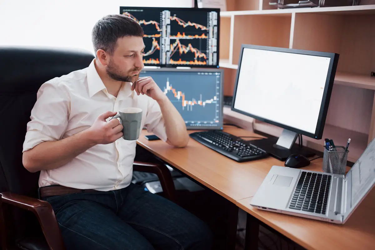 young-businessman-is-sitting-office-table-working-computer-with-many-monitors-diagrams-monitor-stock-broker-analyzes-binary-options-charts-hipster-man-drinking-coffee-studying (1)