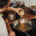 A woman adding garlic to a pan